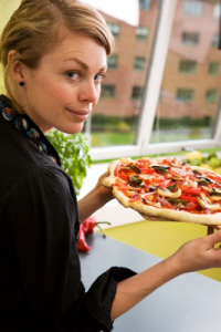 Young woman holding a delicious looking pizza.